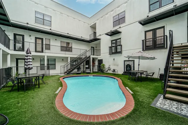 a view of a house with swimming pool lawn chairs and a yard