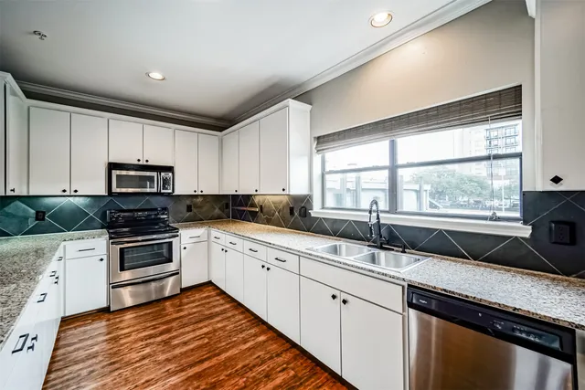 a kitchen with granite countertop a sink wooden cabinets and stainless steel appliances