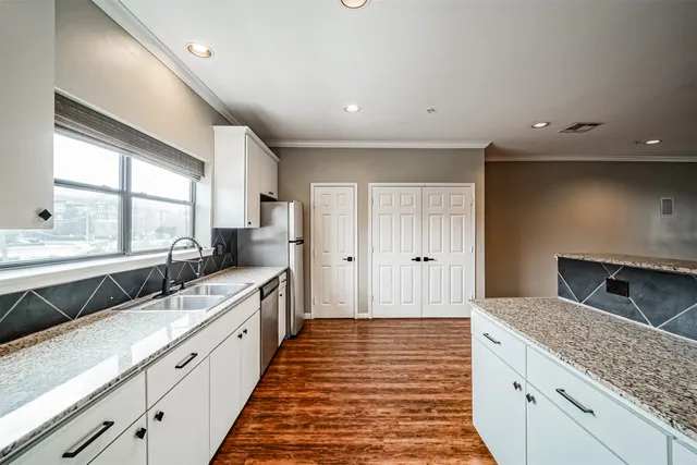 a large kitchen with stainless steel appliances granite countertop a sink and dishwasher a stove with wooden floors