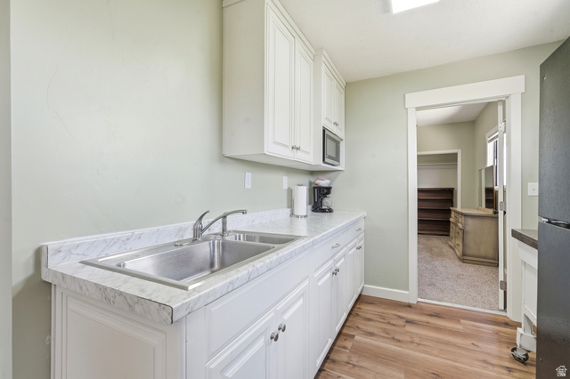 4540 Dingle Road Dingle, ID 83233 - Photo 21 of 22 White cabinetry with silver hardware, stainless steel double basin sink, light-toned countertop, wood-finish flooring, and a built-in microwave