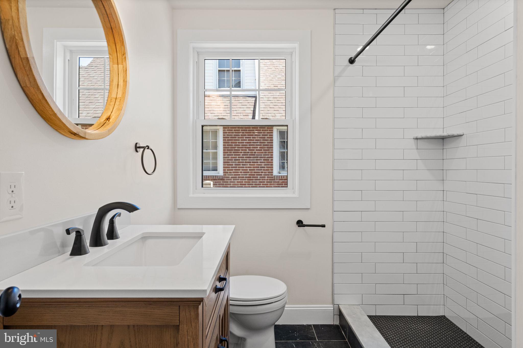 1439 Dorchester Road Havertown, PA 19083 - Photo 35 of 60 a bathroom with a sink a mirror a toilet and a window
