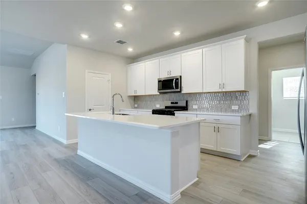 a kitchen with sink a microwave and cabinets