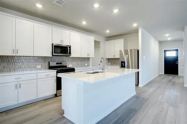 a kitchen with kitchen island a white counter top space cabinets and stainless steel appliances