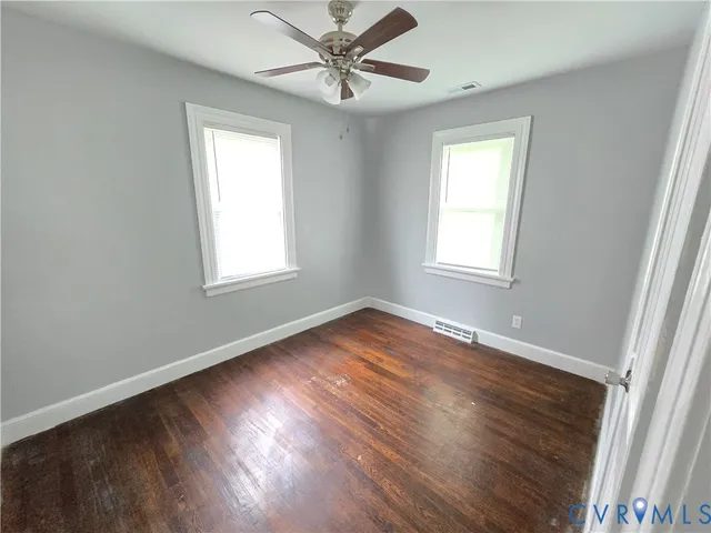 a view of empty room with wooden floor and fan