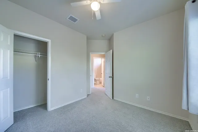 a view of an empty room and a chandelier fan