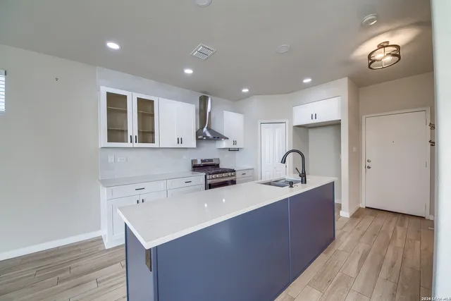 a large kitchen with stainless steel appliances a sink dishwasher a stove a refrigerator and cabinets with wooden floor