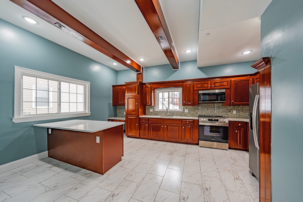 24 Tudor Street Chelsea, MA 02150 - Photo 11 of 36 a large kitchen with stainless steel appliances granite countertop a stove and large refrigerator