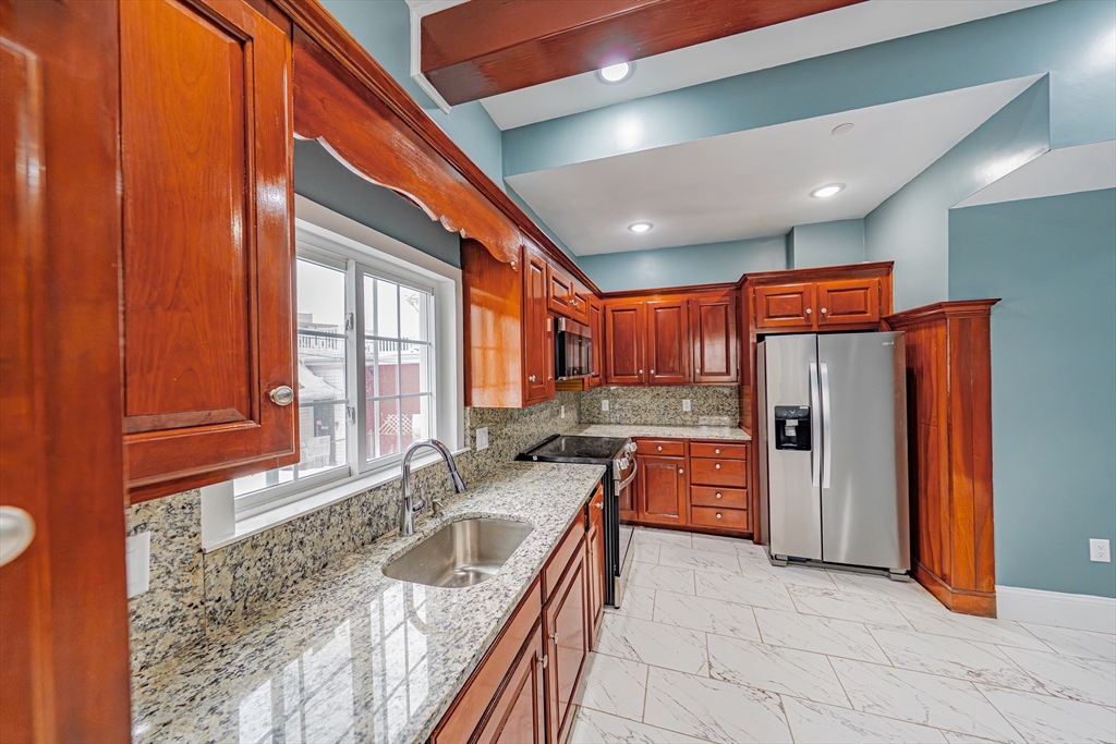 24 Tudor Street Chelsea, MA 02150 - Photo 13 of 36 a kitchen with stainless steel appliances granite countertop a sink window and refrigerator