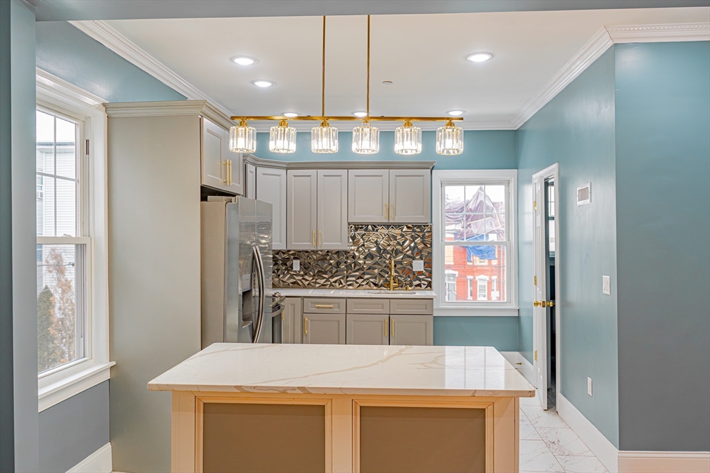 24 Tudor Street Chelsea, MA 02150 - Photo 23 of 36 a kitchen with stainless steel appliances a stove a refrigerator and white cabinets