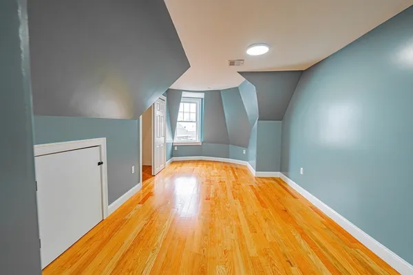 a view of empty room with window and wooden floor