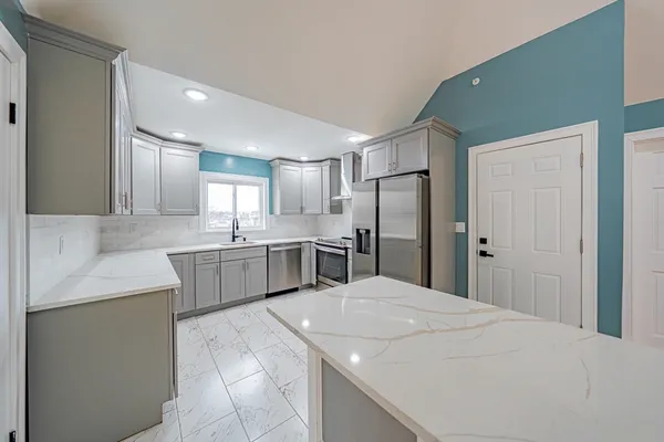 a large kitchen with a refrigerator a sink dishwasher a oven with white cabinets and wooden floor