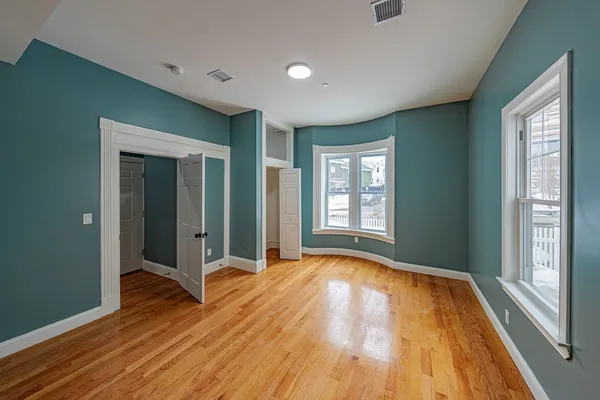 a view of an empty room with glass door and wooden floor