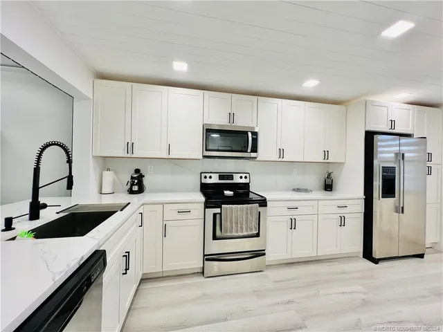 a kitchen with white cabinets and white appliances