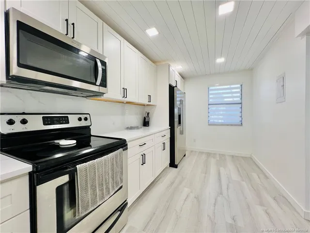 a kitchen with white cabinets and refrigerator