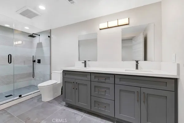 a bathroom with a double vanity sink toilet and shower