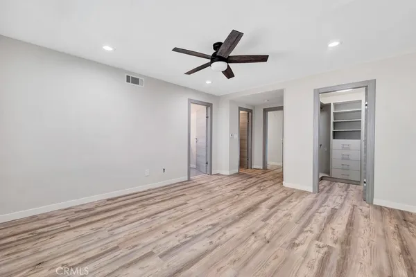 a view of empty room with wooden floor and ceiling fan