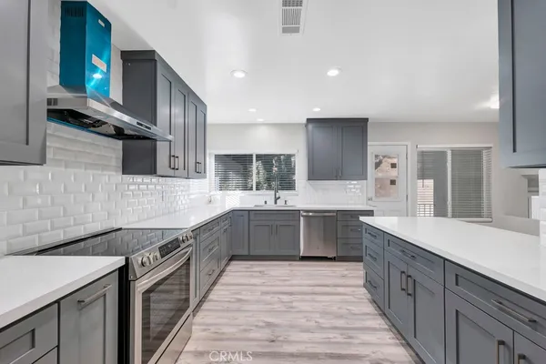 a large kitchen with a large counter top space a sink stainless steel appliances and cabinets