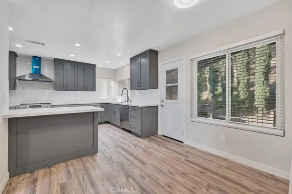 a large kitchen with stainless steel appliances granite countertop a stove a sink and a granite counter tops with wooden floors