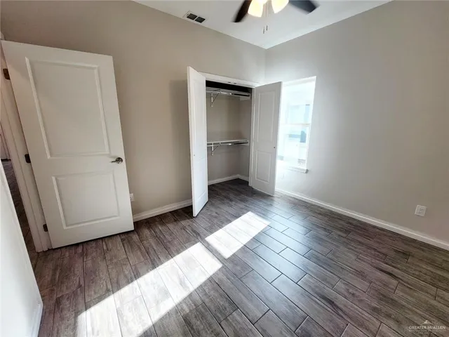 a view of empty room with wooden floor and fan