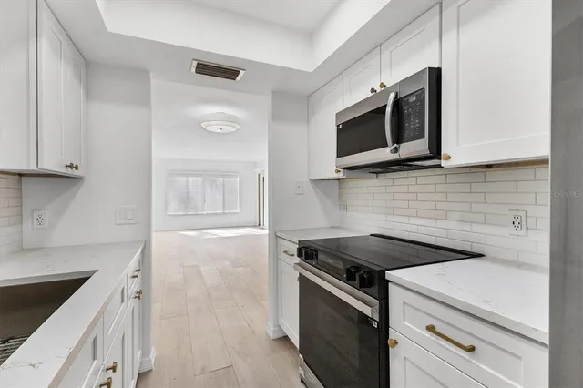a kitchen with stainless steel appliances granite countertop white cabinets and microwave stove