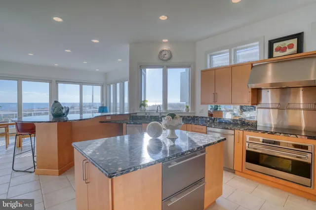a kitchen with stainless steel appliances kitchen island granite countertop a sink and a refrigerator