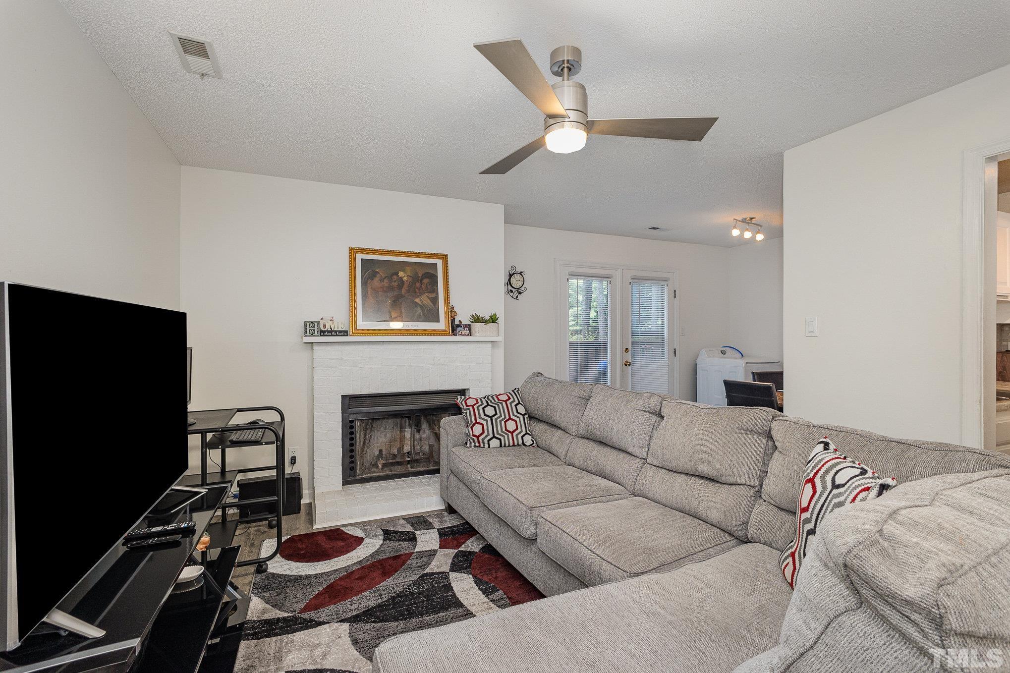 3219 Mill Run, Unit 175 Raleigh, NC 27612 - Photo 5 of 16 a living room with furniture a flat screen tv and a fireplace