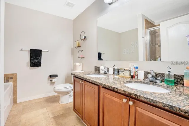 a bathroom with a granite countertop sink mirror vanity and toilet