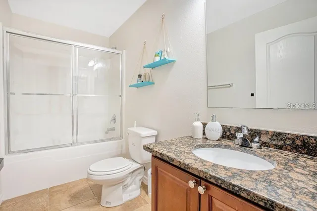 a bathroom with a granite countertop sink a toilet and shower
