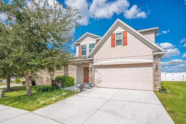 a view of a white house with a yard and large tree