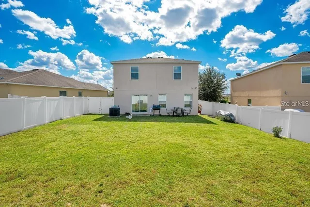 a view of a house with backyard and a tree