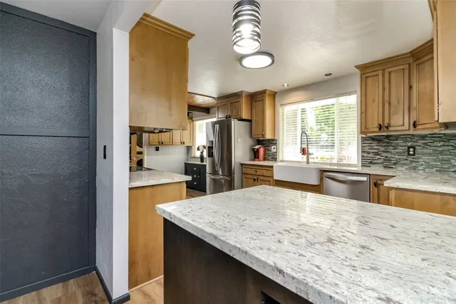 a kitchen with stainless steel appliances granite countertop a refrigerator a stove and a sink