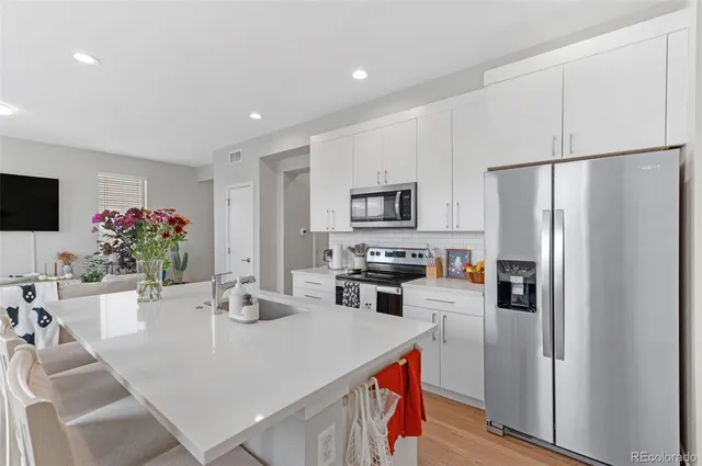 a kitchen with stainless steel appliances a refrigerator a stove a microwave a dining table and chairs