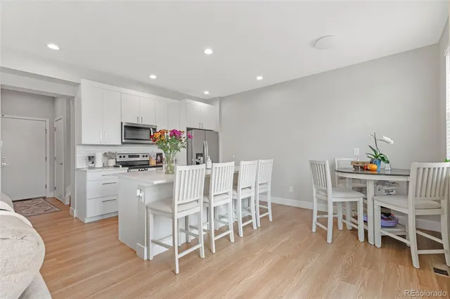a kitchen with stainless steel appliances a dining table chairs and wooden floor