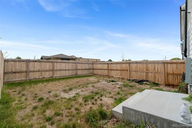 a view of a house with backyard and wooden fence