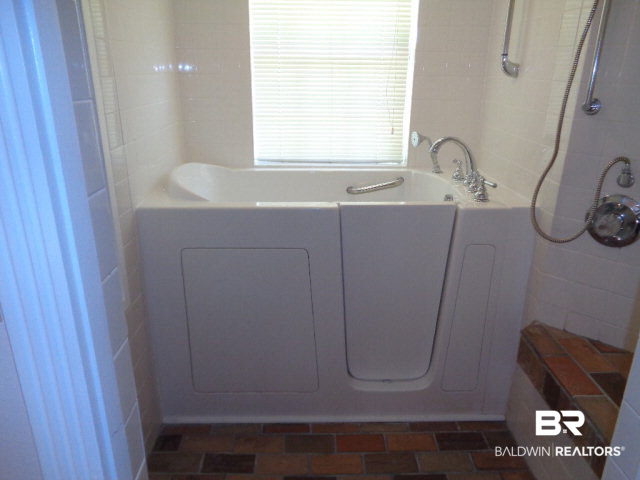 28202 Vargo Lane Elberta, AL 36530 - Photo 19 of 45 This is in the bathroom on the East end of the home. Walk-in bathtub. 2 showers, bench and shelving. Brick floor.