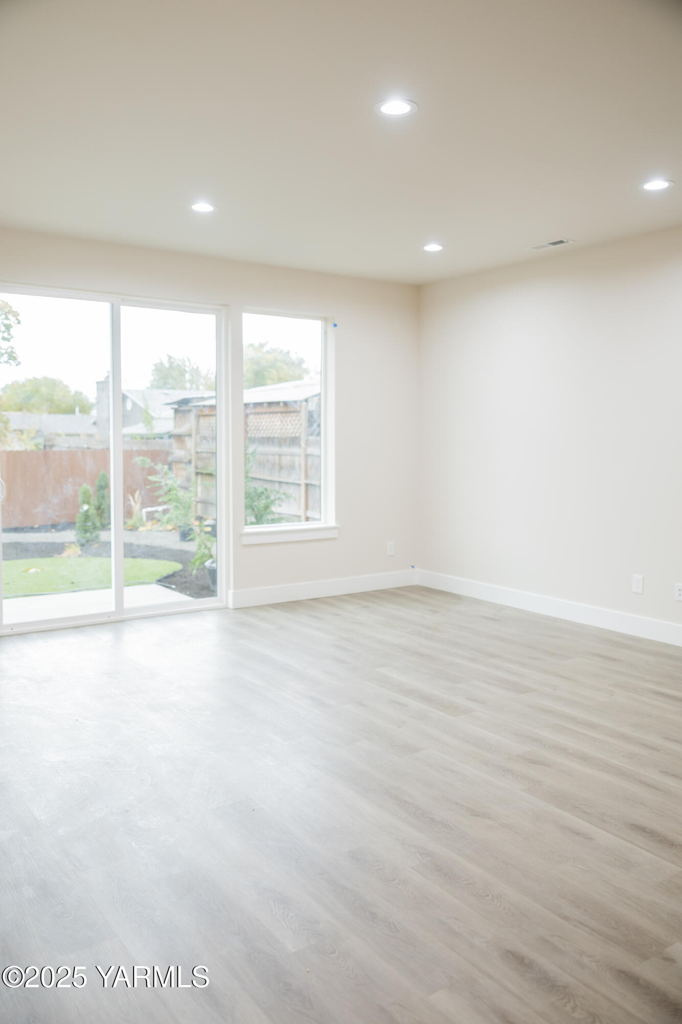 209 Victoria Street Sunnyside, WA 98944 - Photo 5 of 24 an empty room with wooden floor and windows