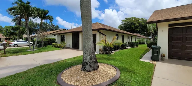 a front view of a house with a yard and trees
