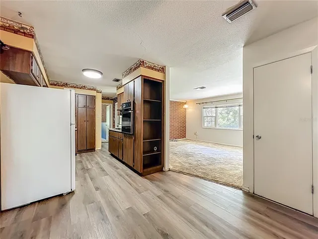 a view of a kitchen with wooden floor and a refrigerator