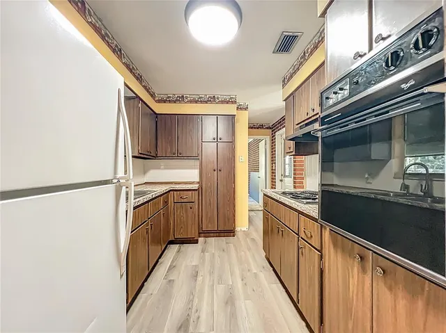 a kitchen with stainless steel appliances granite countertop a refrigerator a stove and a sink with wooden floor