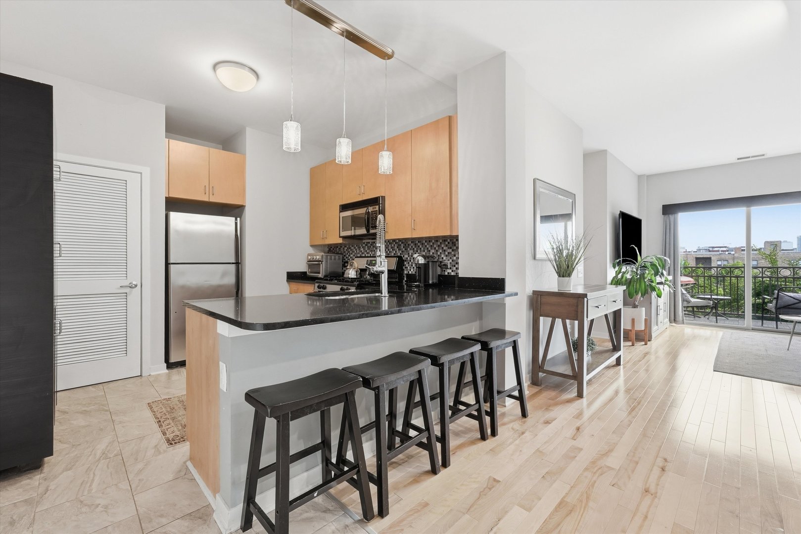 1155 West Roosevelt Road, Unit 404 Chicago, IL 60608 - Photo 5 of 30 a kitchen with stainless steel appliances granite countertop a stove a refrigerator a kitchen island a dining table and chairs with wooden floor