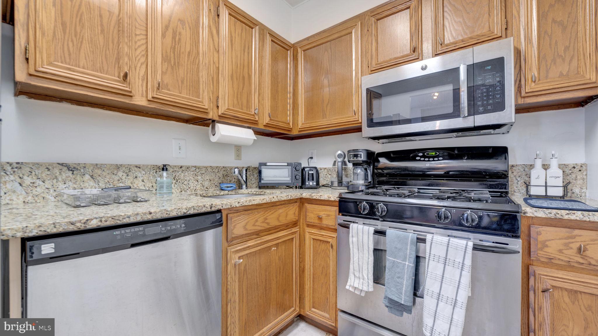 490 M Street Southwest, Unit W110 Washington, DC 20024 - Photo 5 of 11 a kitchen with stainless steel appliances granite countertop a stove a sink and a microwave
