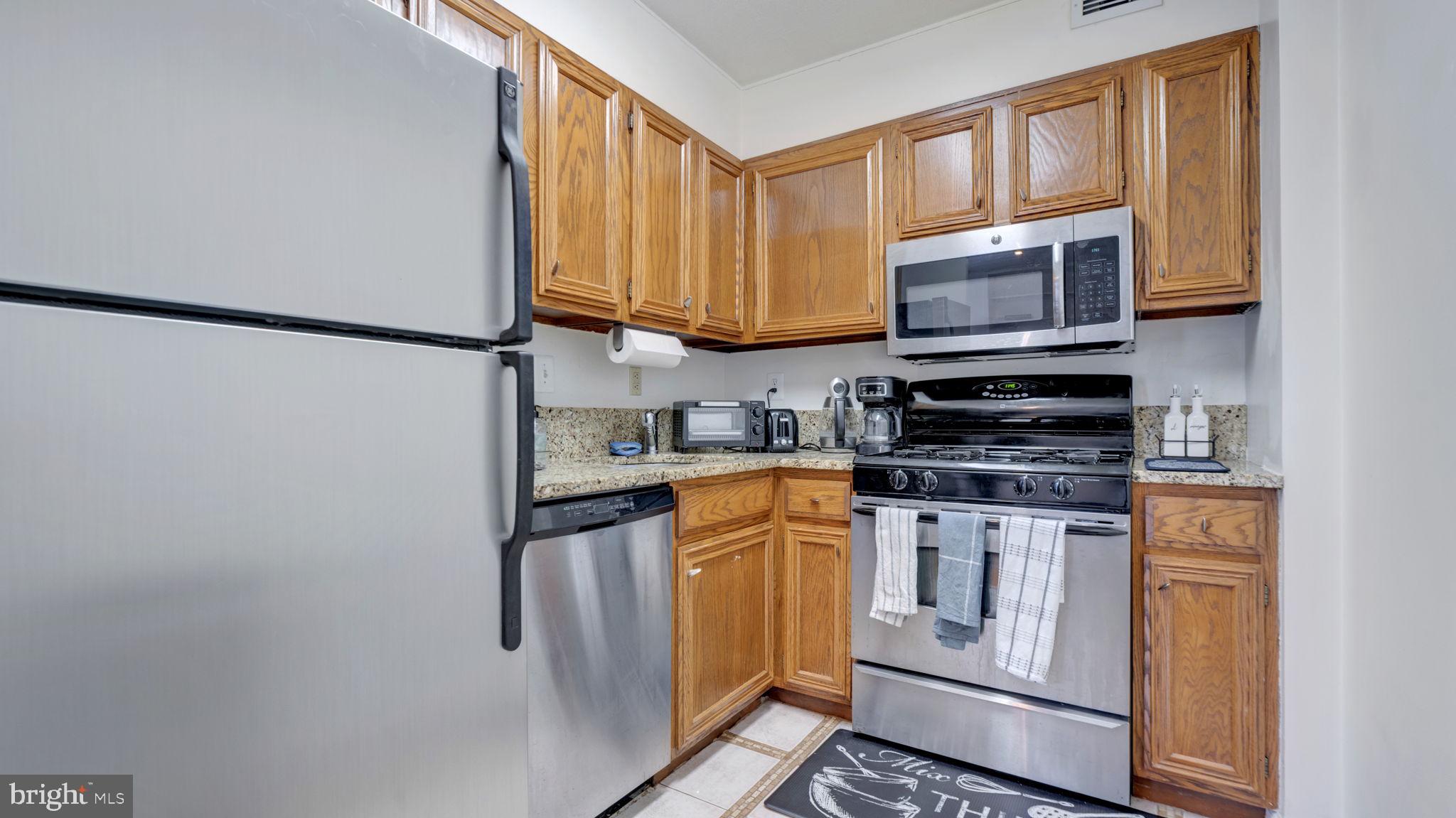 490 M Street Southwest, Unit W110 Washington, DC 20024 - Photo 6 of 11 a kitchen with stainless steel appliances granite countertop a stove a sink and a microwave