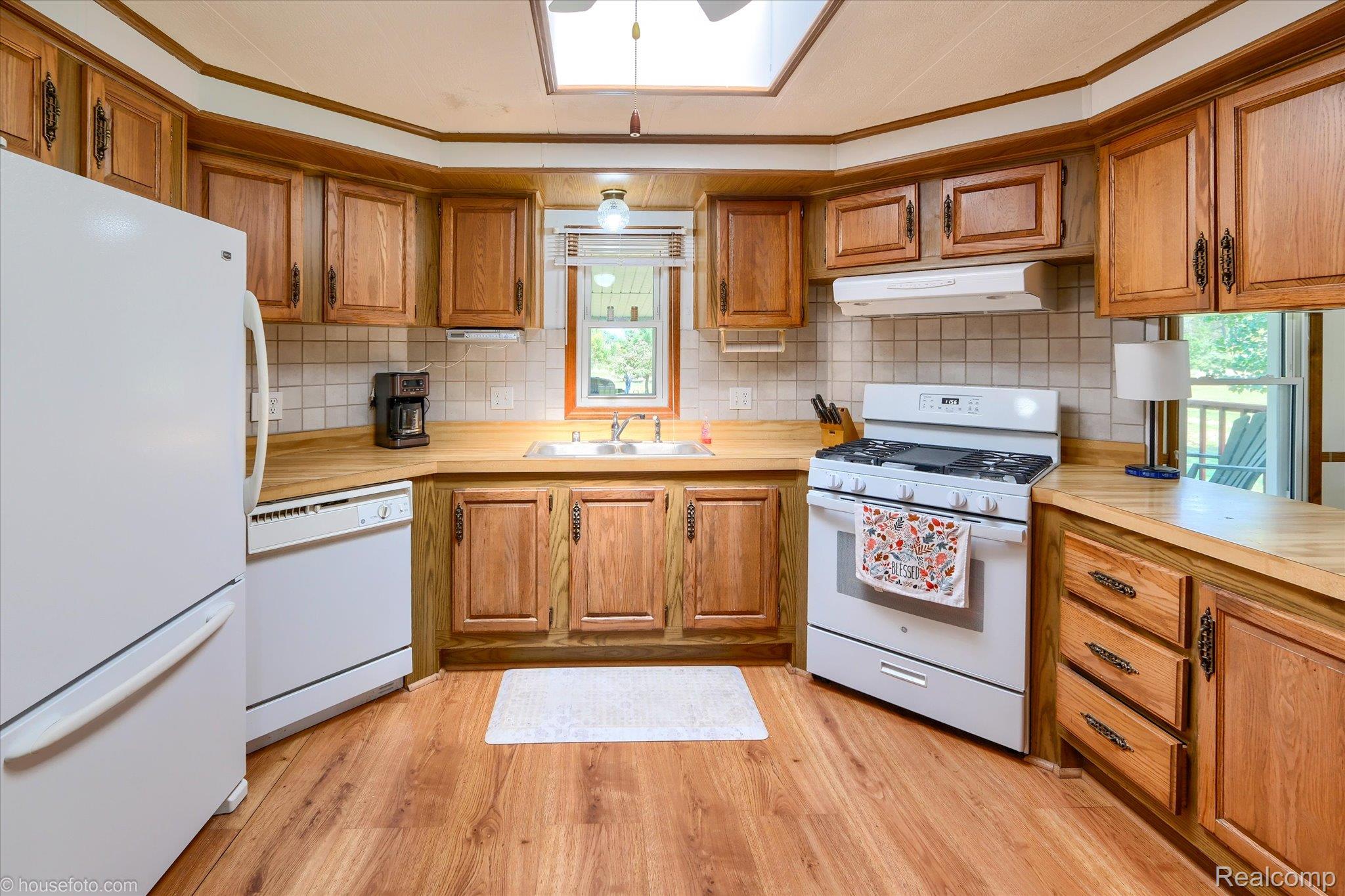 13566 Kaufman Road Capac, MI 48014 - Photo 14 of 50 Kitchen featuring white appliances, brown cabinetry, light countertops, and crown molding