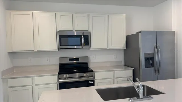 a kitchen with appliances a refrigerator and cabinets