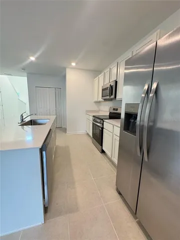 a kitchen with kitchen island a counter top space appliances and a sink