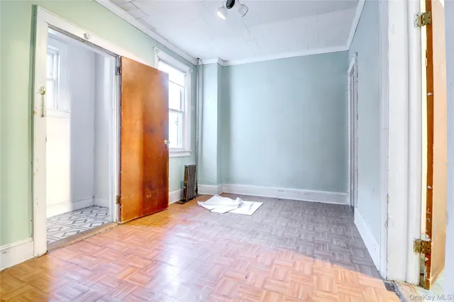 a view of an empty room with wooden floor and a window