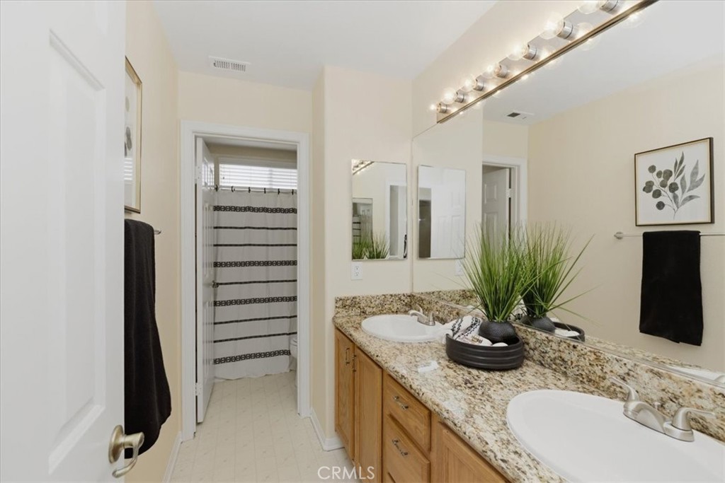 39264 Memory Drive Murrieta, CA 92563 - Photo 17 of 35 a bathroom with a granite countertop sink a mirror and shower