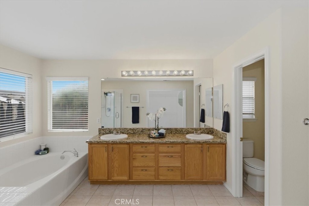39264 Memory Drive Murrieta, CA 92563 - Photo 26 of 35 a bathroom with a granite countertop sink a mirror a bathtub and shower