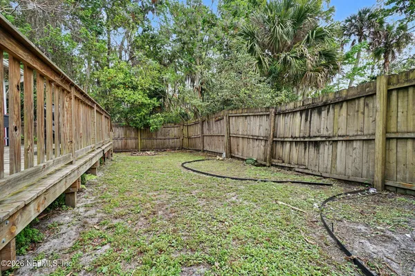 a view of a backyard with a tree and wooden fence
