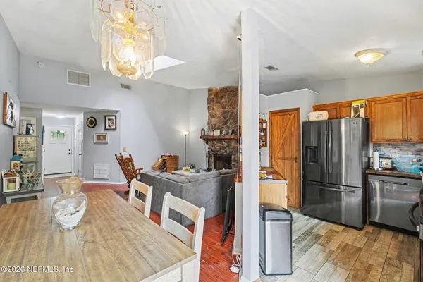 a kitchen with stainless steel appliances granite countertop a refrigerator a microwave oven a dining table and chairs with wooden floor